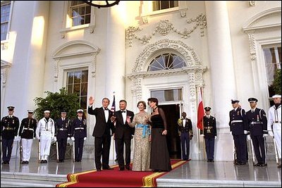 Flanked by some of America’s finest servicemen, President Bush and Mrs. Bush wave to photographers with President Kwasniewski and Mrs. Kwasniewska as they welcome Poland’s first couple to the State Dinner July 17. White House photo by Susan Sterner.