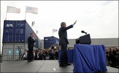 As Homeland Security Secretary Tom Ridge stands nearby, President George W. Bush waves to the audience after delivering remarks on homeland security at the Port of Charleston, S.C., Feb. 5, 2004.