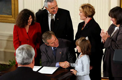 After signing a proclamation recognizing October as Domestic Violence Month, President George W. Bush shakes hands with Monique Blais, 7, the young artist who designed the Stop the Violence postage stamp in the East Room Oct. 8, 2003. 