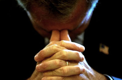 President George W. Bush bows his head in prayer before starting his Cabinet Meeting July 31, 2002.