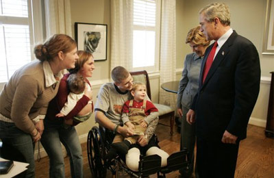 President George W. Bush and Laura Bush talk with U.S. Army Sgt. Dale Beatty of Statesville, N.C., and, from left, sister-in-law Wendolyn Summers, wife Belinda Beatty, son Lucas, 6 months old, and son Dustin, 2 years old, during a visit to the Fisher House at Walter Reed Army Medical Center in Washington, D.C., Tuesday, Dec. 21, 2004. President Bush presented Sgt. Beatty The Purple Heart for injuries he sustained while serving in Operation Iraqi Freedom.  White House photo by Paul Morse