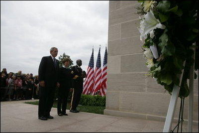 President George W. Bush and Laura Bush, accompanied by Sgt. Timothy Boyd of the Military District of Washington, stand before a memorial wreath Monday, Sept. 11, 2006, during a moment of silence at the Pentagon in Arlington, Va., to commemorate the fifth anniversary of Sept. 11, 2001 attacks.
