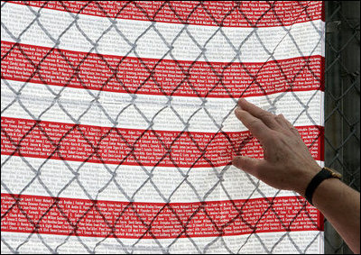 A visitor at the fence overlooking Ground Zero touches an American flag printed with names of those who were killed during the September 11th terrorist attacks Sunday, September 10, 2006. President and Mrs. Bush also visited the site Sunday to mark the fifth anniversary of the attacks. 