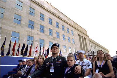 Sitting in front of the rebuilt section of the Pentagon, service personnel and families listen to President George W. Bush at the Pentagon Observance Wednesday, Sept. 11. "One year ago, men and women and children were killed here because they were Americans. And because this place is a symbol to the world of our country's might and resolve," said the President. "Today, we remember each life. We rededicate this proud symbol and we renew our commitment to win the war that began here."