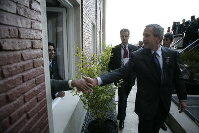 President George W. Bush reaches out for the hand of a well-wisher after participating in the 2005 class photo during opening ceremonies Friday, Nov. 4, 2005, of the Summit of the Americas in Mar del Plata, Argentina.