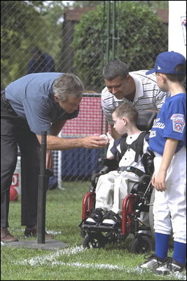President George W. Bush greets Kevin Fulcher, Jr., 7 year old son of WHCA Tech. Sgt. Kevin Fulcher, Sr., during a White House Tee Ball (t-ball) game on the South Lawn between the Waynesboro, Virginia Little League Challenger Division Sand Gnats (Blue Team) vs. the East Brunswick, New Jersey Babe Ruth Buddy Ball League Sluggers (Red Team) September 22, 2002.