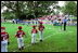 Kicking off the fourth season of White House Tee Ball, President Bush speaks during the first game of the 2004 season June 13, 2004. President Bush started the league to encourage foster a spirit of teamwork and service in America's youth.