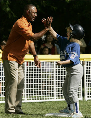A player from the District 12 Little League Challengers of Williamsport, Pa., is given a high-five from baseball star and Tee Ball third base coach Ozzie Smith, Sunday, July 24, 2005, during a Tee Ball game on the South Lawn of the White House.
