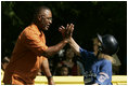 A player from the District 12 Little League Challengers of Williamsport, Pa., is given a high-five from baseball star and Tee Ball third base coach Ozzie Smith, Sunday, July 24, 2005, during a Tee Ball game on the South Lawn of the White House.