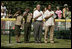 President George W. Bush is joined by Barry Larkin, White House Tee Ball Commissioner of the Game and Young Marines as they stand for the National Anthem Sunday, June 26, 2005, during "Tee Ball on the South Lawn."