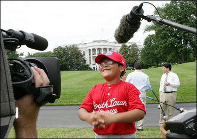 A player with the Cramer Hill Little League Red Sox of Camden, N.J., is the center of media attention on the South Lawn of the White House after playing Monday, June 30, 2008, in the opening game of the 2008 Tee Ball on the South Lawn, with his teammates against the Jose M. Rodriguez Little League Angels of Manatí, Puerto Rico.