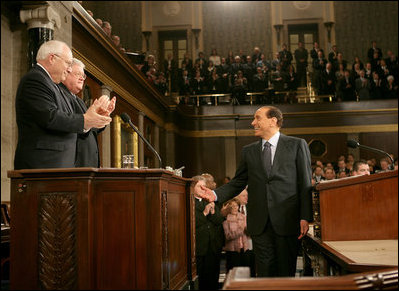 Italian Prime Minister Silvio Berlusconi smiles at Vice President Dick Cheney and House Speaker J. Dennis Hastert, as he gestures in response to a warm welcome given by members of a joint session of Congress, Wednesday, March 1, 2006.