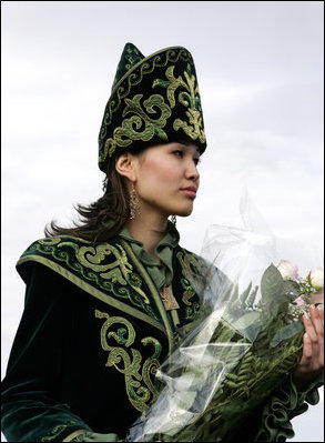 A Kazakh woman adorned in ceremonial dress holds a bouquet of flowers as Vice President Dick Cheney arrives in Astanta, Kazakhstan, Friday, May 5, 2006.