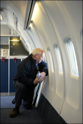 Vice President Dick Cheney kneels to look out of the window of Air Force Two, Feb. 19, 2007, while en route to the pacific region for visits to Tokyo, Guam and Sydney. White House photo by David Bohrer