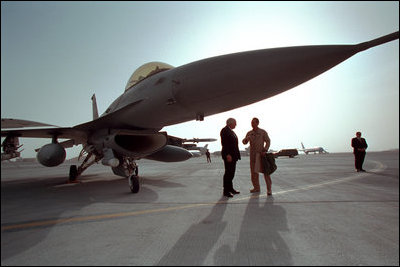 Standing under a F-16 fighter jet, Vice President Dick Cheney talks with an Air Force pilot during a tour of the Al-Udeid Airbase in Qatar, March 17, 2002.