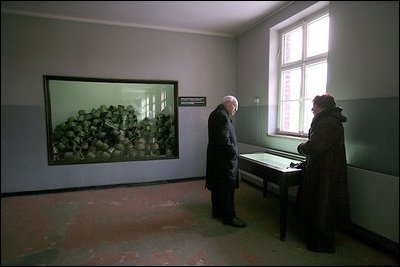 Standing in a room formerly used as barracks for Nazi prisoners, a museum guide explains to Vice President Dick Cheney about the atrocities committed there at the Auschwitz-1 Nazi concentration camp, near Krakow, Poland, Friday, Jan. 28, 2005. The window at left shows a display of empty cans of Zyklon-B gas used against former prisoners. Vice President Cheney was there to take part in ceremonies commemorating the 60th Anniversary of the liberation of the Auschwitz camps. 