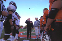 Vice President Dick Cheney flips a coin to begin the homecoming football game between the Natrona County High School Mustangs, right, and Cheyenne Central High School Indians, left, in Casper, Wyo., Sept. 20, 2002. The Mustangs won the game 24-6.