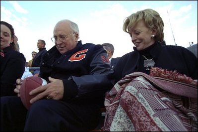 Vice President Dick Cheney signs a football for a Natrona County High School student while watching the school's homecoming game with his high school sweetheart, Lynne Cheney, in Casper, Wyo., Sept. 20, 2002. 