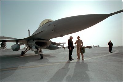 Standing under a compact, 16-foot tall F-16 fighter jet, Vice President Dick Cheney talks with an Air Force pilot on his tour of the Al-Udeid Airbase in Qatar, March 17, 2002.