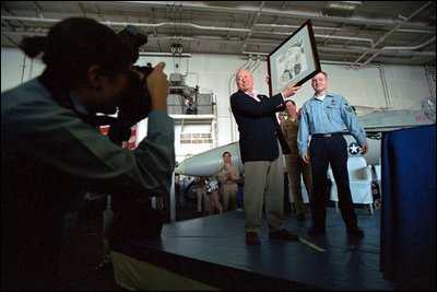 Sharing the stage with artist Chad DuLac, Vice President Dick Cheney displays a drawing of himself while aboard the USS Stennis Aircraft Carrier March 15, 2002.