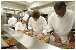 White House Executive Chef, Cristeta "Cris" Comerford, background-left in chef's hat, helps prepare trays of food, Wednesday, Nov. 2, 2005, in the White House kitchen, in preparations for the official dinner for the Prince of Wales and Duchess of Cornwall.