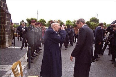 President Bush salutes a veteran during a Memorial Day service at Notre Dame De La Paix Church at Normandy, France, May 27, 2002. The President and Mrs. Bush visited the beach and attended American ceremony in honor of D-Day veterans. "Only a man who is there, charging out of a landing craft, can know what it was like," said the President in his remarks. "For the entire liberating force, there was only the ground in front of them -- no shelter, no possibility of retreat. They were part of the largest amphibious landing in history, and perhaps the only great battle in which the wounded were carried forward."